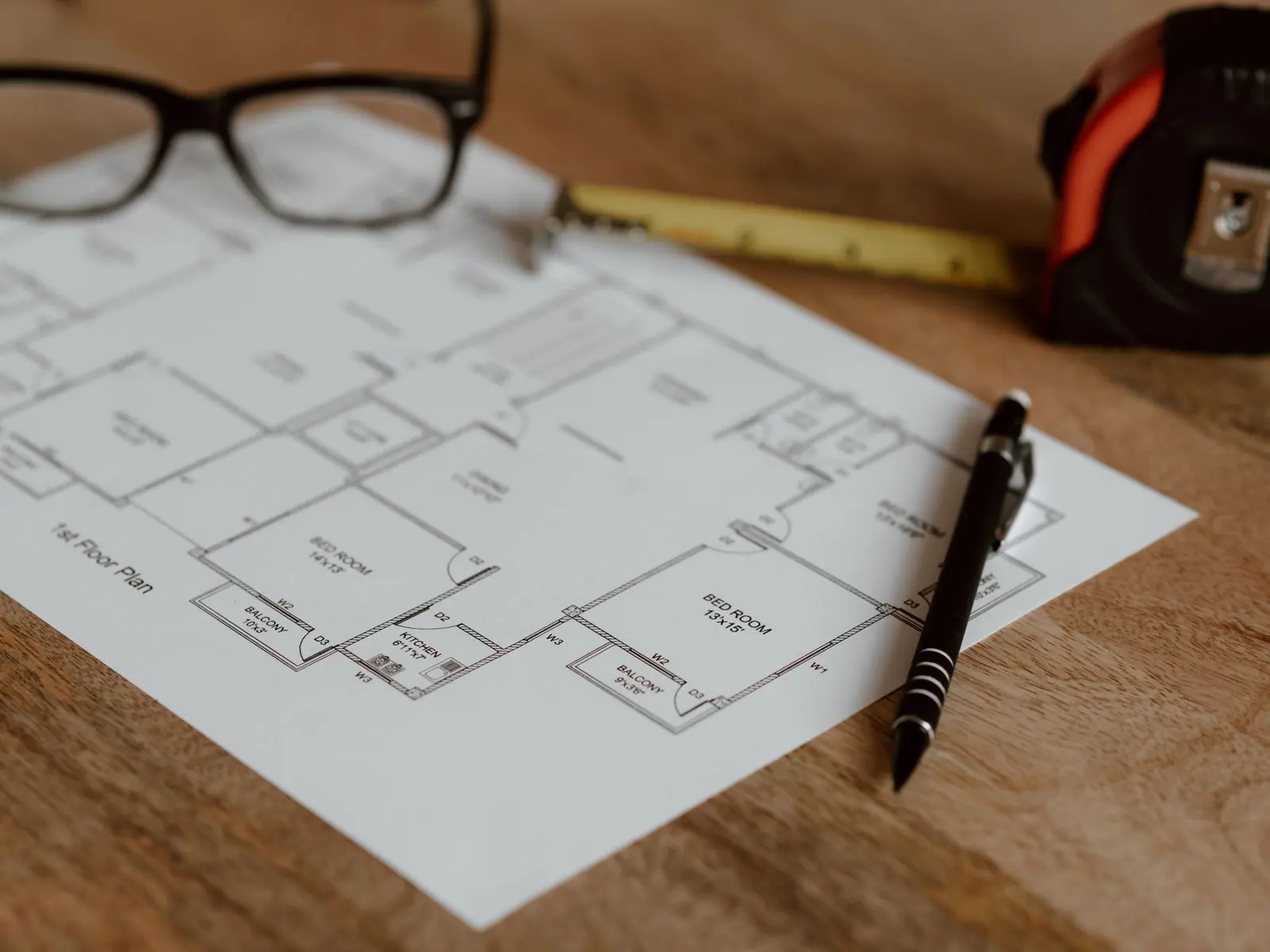 Floor plan drawing on a desk with a tape measure and glasses